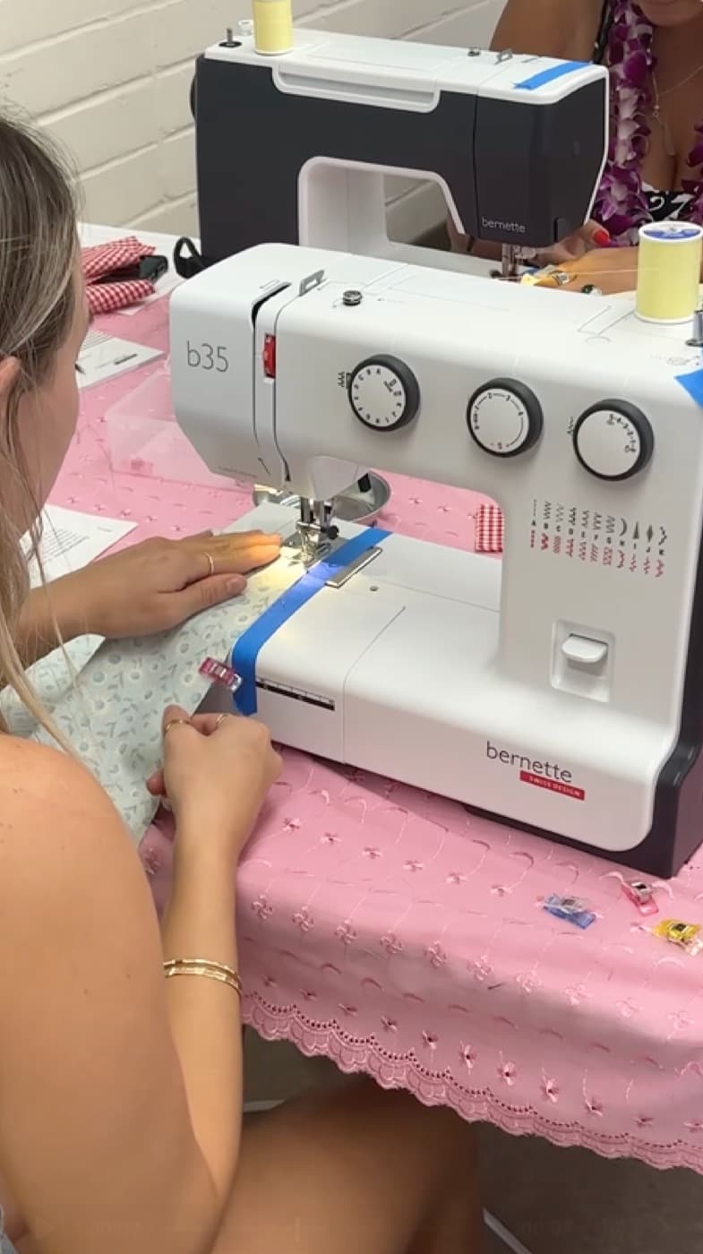 Student guiding floral fabric through a Bernette sewing machine