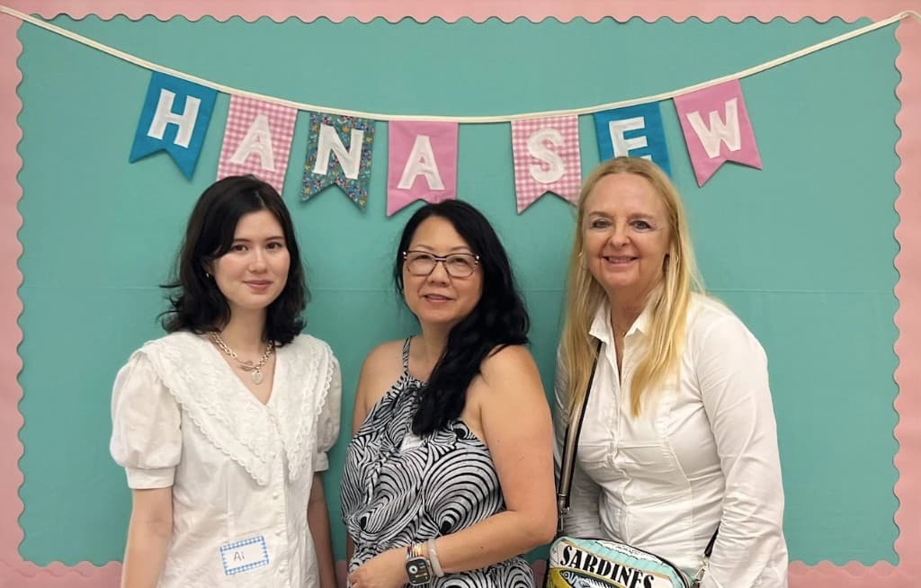 The Hana Sew founders standing in front of a handmade HANA SEW fabric banner